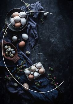 an overhead view of eggs in bowls on a table with blue cloth and greenery