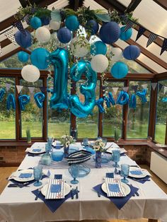 the table is set with blue and white decorations for an elegant birthday party at home