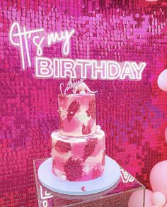 a pink birthday cake sitting on top of a table