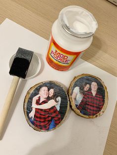 two wooden slices with pictures on them next to a paintbrush