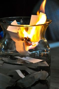 a glass vase filled with water and burning paper