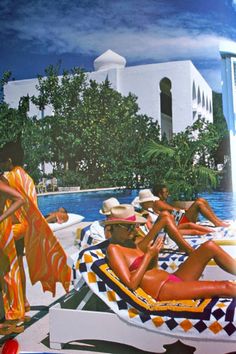 a group of people in bathing suits and hats sitting on lounge chairs next to a pool