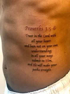 the back of a man's stomach with a bible verse written on his side