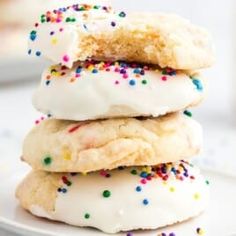 a stack of cookies with white frosting and sprinkles on a plate