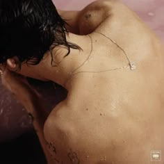 a man with his back turned to the camera, sitting in a pink bathtub