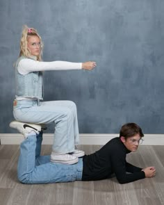 a woman sitting on the back of a man who is kneeling down and pointing at her