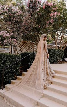 a woman in a wedding dress is standing on some steps with her veil draped over her head