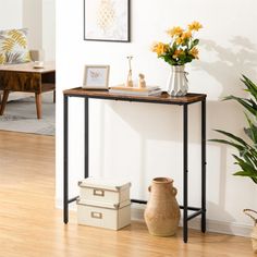 a table with some vases and flowers on it in front of a white wall