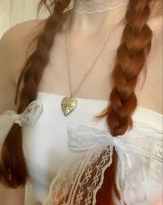 a woman with red hair wearing a white dress and holding a heart shaped pendant in her hand