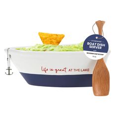 a bowl filled with guacamole and tortilla chips next to a wooden spoon