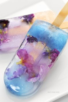 two popsicles with flowers on them sitting on a plate