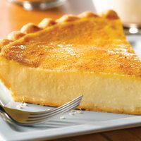 a piece of pie sitting on top of a metal plate next to a fork and cup