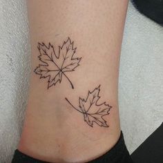 a leaf tattoo on the ankle is shown in black and grey colors, with two small leaves attached to it