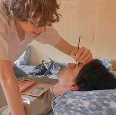 a woman is getting her hair done by a young man in the bed while another person looks on