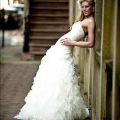 a woman in a wedding dress leaning against a wall