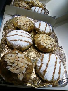 several pastries are sitting on a metal platter covered in powdered sugar and almonds