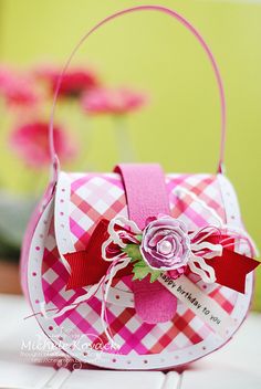 a pink and white checkered bag with a flower in it's center sitting on top of a table