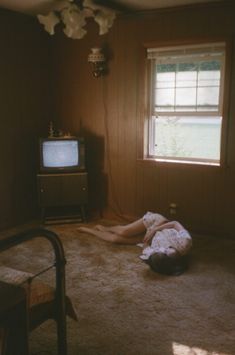 a person laying on the floor in front of a window with a tv set behind them