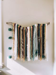 a wall hanging made out of yarn and feathers