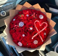 a bouquet of red roses in the shape of a heart with a candy cane and snowflakes