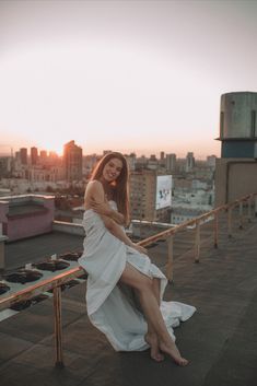 a woman in a white dress sitting on top of a roof