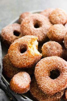 a plate filled with sugar covered donuts on top of a table next to a napkin