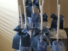 several blue apples in clear boxes with bows and pearls on them, tied together by twine