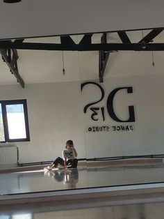 a woman sitting on the floor in front of a dance studio