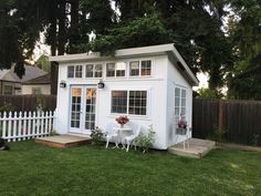 a small white shed sitting on top of a lush green field