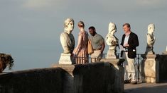 three men standing next to each other in front of statues on top of a bridge