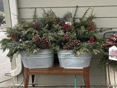 two metal buckets filled with pine cones and greenery