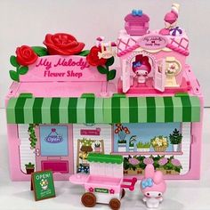 a pink toy house with flowers on the roof and furniture in it's display case