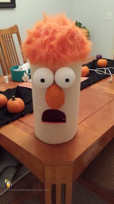 a table topped with a plastic cup covered in orange hair and an angry man face