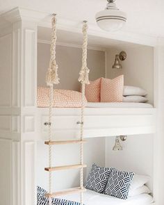 a white bunk bed with rope hanging from it's sides and pillows on the bottom