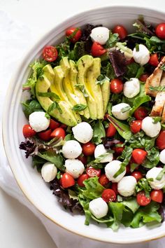 a salad with chicken, tomatoes, avocado and mozzarella in it