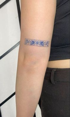 a woman's arm with a tattoo on it that has blue flowers and leaves