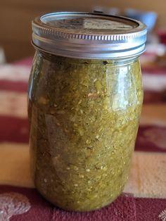 a jar filled with green stuff sitting on top of a red and white table cloth