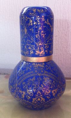 a blue and gold vase sitting on top of a table next to a white wall