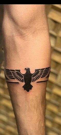 a man's leg with a black bird tattoo on the side of his leg