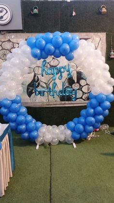 a blue and white balloon arch with a happy birthday sign