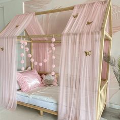 a canopy bed with pink curtains and pillows