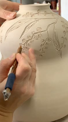 a person working on a vase with a pen