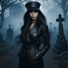 a woman in a black leather coat and hat standing next to tombstones at night