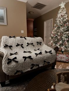 a living room with a couch covered in black bows and a christmas tree behind it