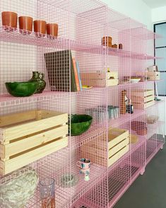 a pink shelf filled with lots of wooden crates