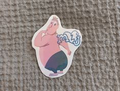 a sticker with a cartoon character on it sitting on top of a cloth covered surface