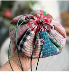 a hand holding a small pouch filled with fabric and string wrapped around the inside of it