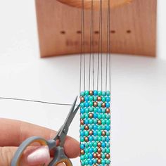 someone is using scissors to make beading on a piece of string with beads and wood