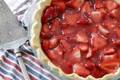 a pie with strawberries in it sitting on top of a blue and white towel