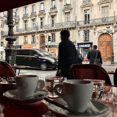 a table with coffee cups and saucers on it in front of a car passing by